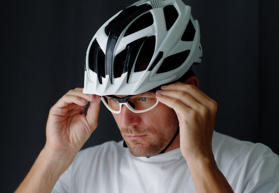 Close-up Portrait shot, biker putting on a glasses and adjusting. Gray background.